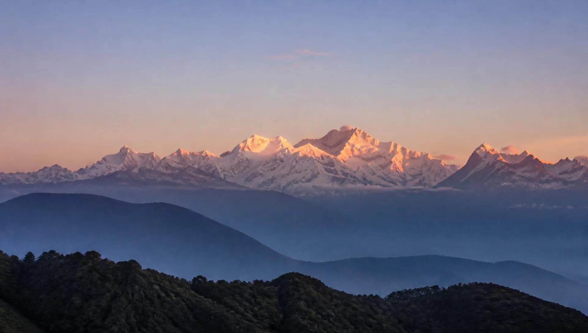 Kanchenjunga snow peaks at sunrise above forested ridges seen from Pelling, West Sikkim