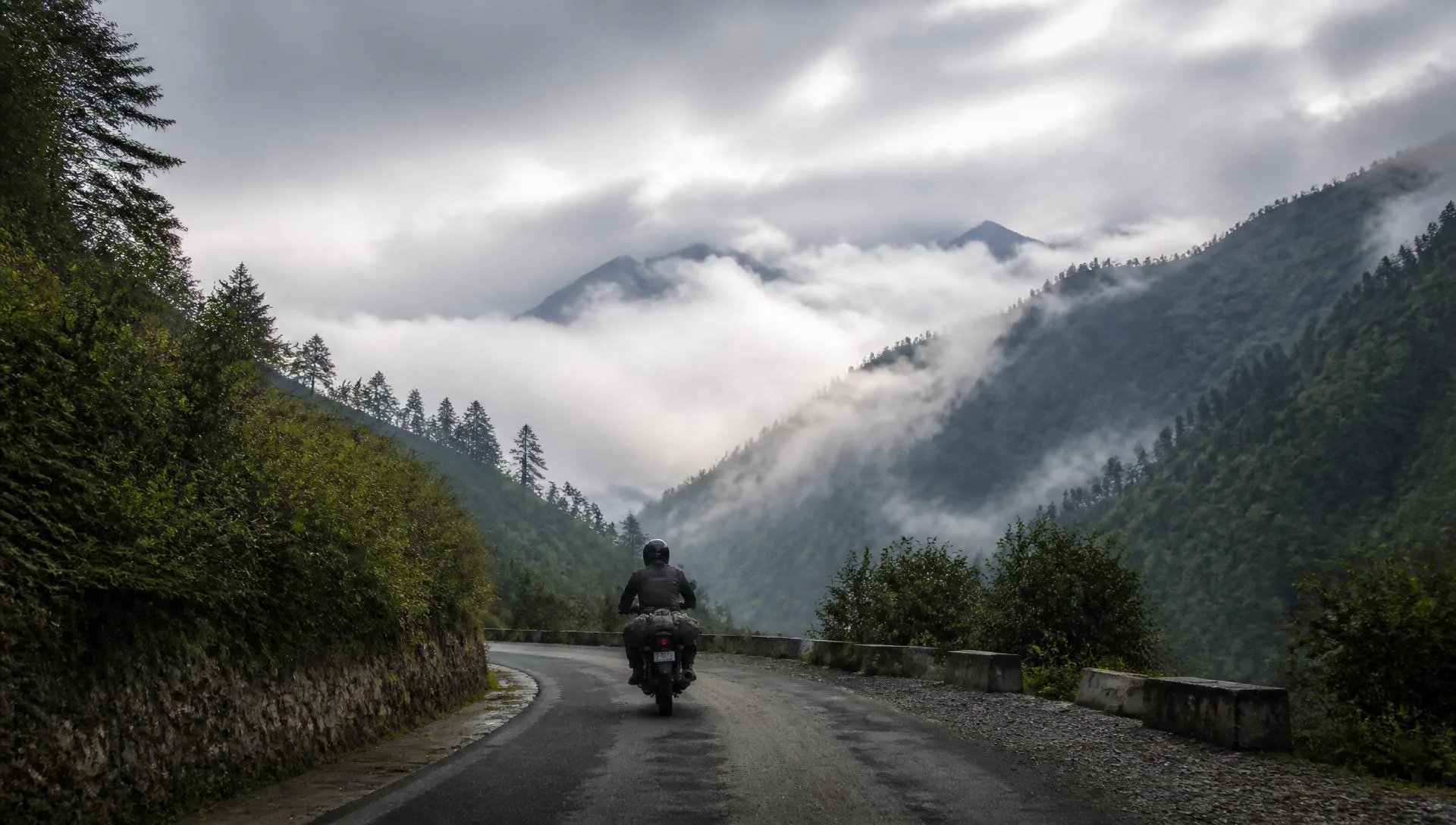 Motorcycle rider on a misty Himalayan mountain road in Sikkim